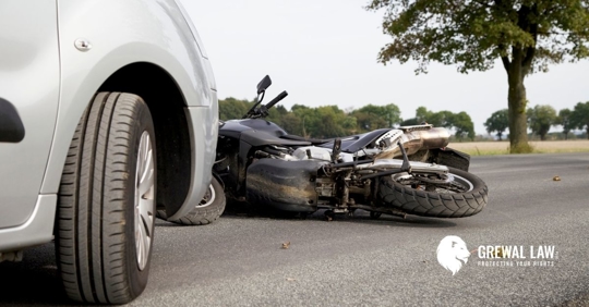 A motorcycle pinned underneath a car.